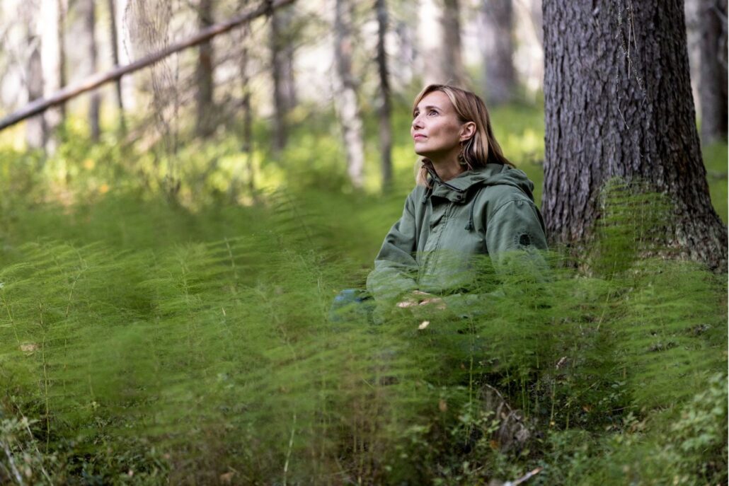 nainen istuu metsässä