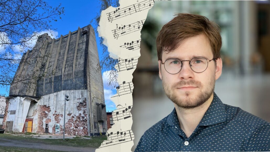 silmälasipäinen mies, nuottipaperia ja korkea betoninen rakennus