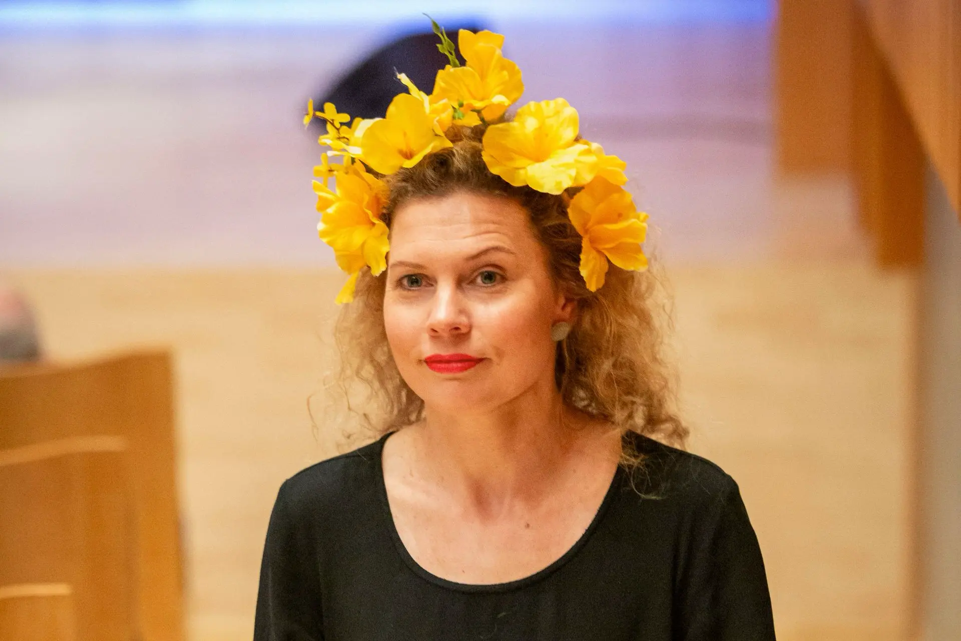 kiharahiuksinen nainen keltainen kukkaseppele päässään, taustalla konserttisali