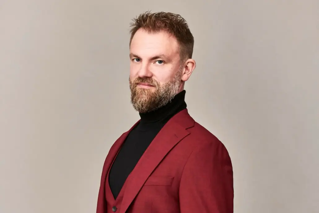 rintakuva miehestä, jolla on parta ja viininpunainen takki