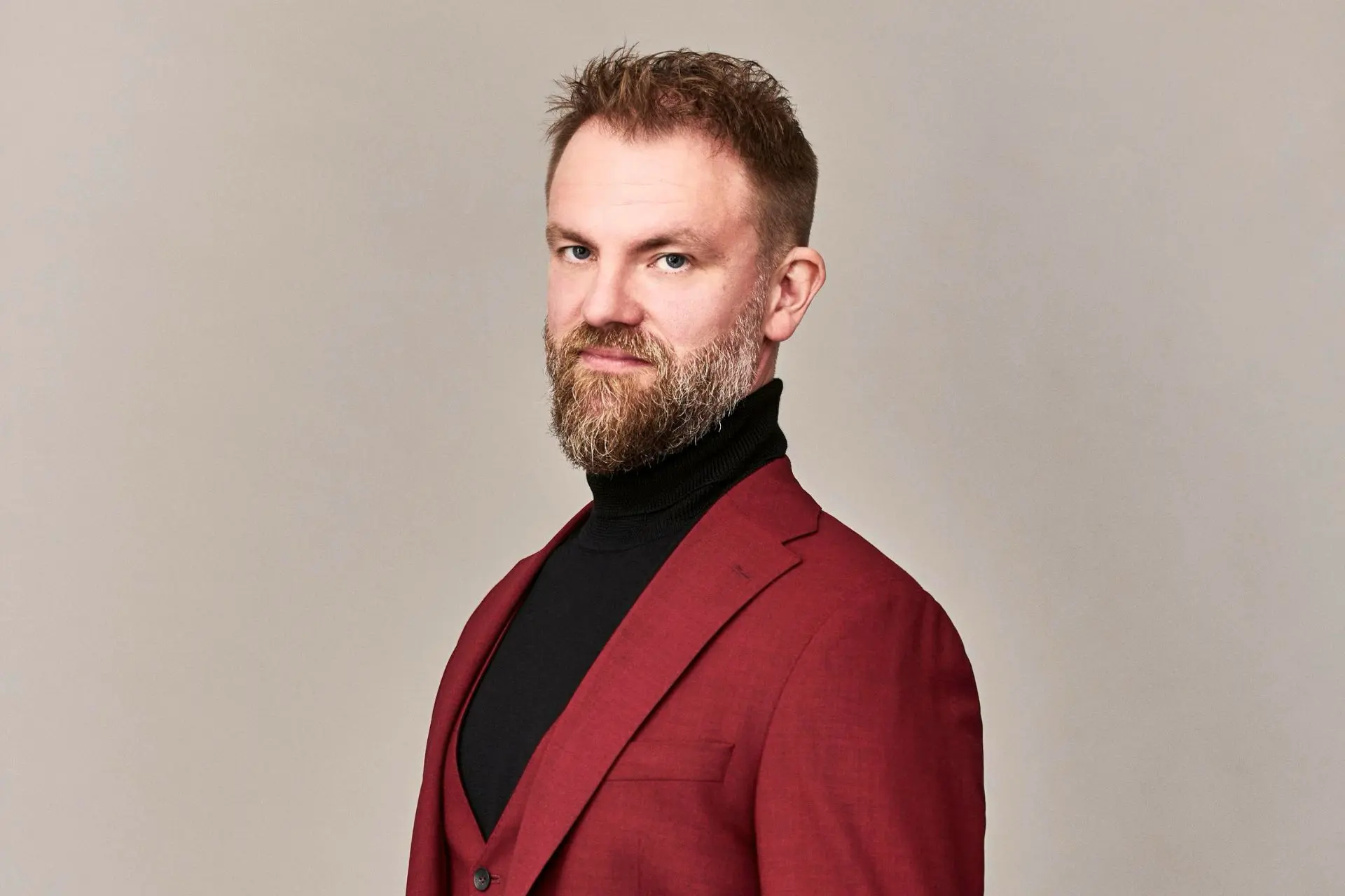 rintakuva miehestä, jolla on parta ja viininpunainen takki